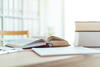 an open book next to a stack of books